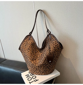 Macro detail of the leopard print canvas tote bag with dark brown leather trim and handles