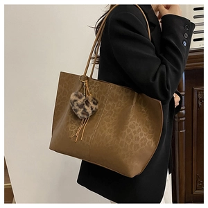 Brown faux leather tote bag with subtle leopard print and heart-shaped plush charm