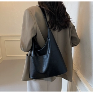 Detailansicht der schwarzen Hobo-Tasche aus genarbtem Leder mit großem Vorderfach an einem Model