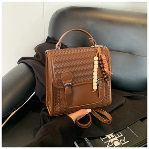 Close-up of brown woven leather backpack with a decorative wooden bead charm
