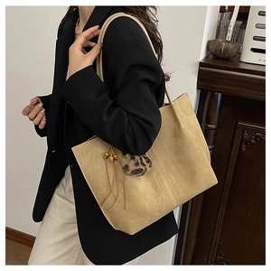Close-up of khaki tote bag featuring a stylish leopard fur ball and leather tassel detail