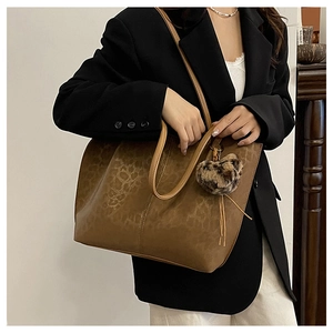 Detail of leopard print tote bag with plush heart charm on a shoulder strap