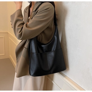 Detail einer schwarzen Shopper-Tasche aus Leder mit Fronttaschen an einem Modell