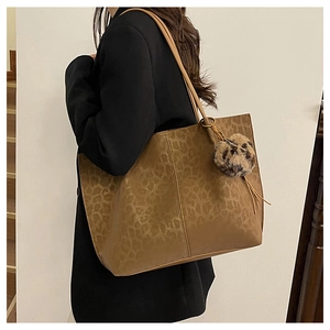 Brown vintage leopard print tote bag with plush charm shown worn on the shoulder