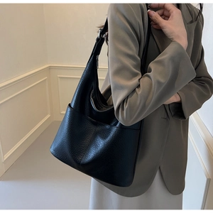 Detailaufnahme der schwarzen Schultertasche aus Leder mit Lychee-Muster am Model