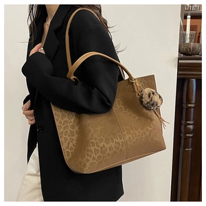 Detail of large brown tote bag with subtle leopard print and plush charm accessory