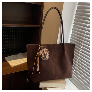 Detail of dark brown faux suede tote bag with leopard print pompom and tassel charm
