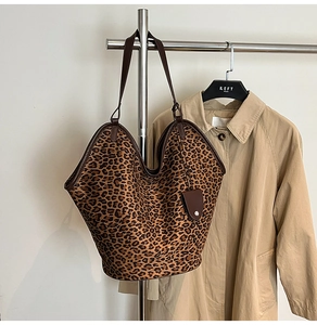 Detailed view of leopard print tote bag with brown leather trim on a metal hanger