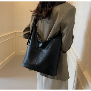 Schwarze Hobo-Schultertasche mit grober Ledertextur, getragen von einem weiblichen Model