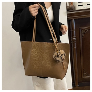 Detail of large brown tote bag with leopard print texture and heart plush charm