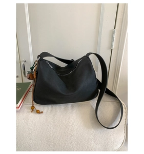 Detail der minimalistischen schwarzen Leder-Hobo-Tasche mit Perlen- und Blumenanhänger