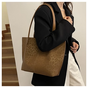 Detailed view of a large leopard print tote bag worn as a shoulder bag on a model