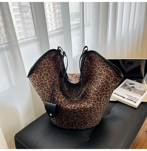 Detail shot of large leopard print tote bag with black trim on a black leather seat