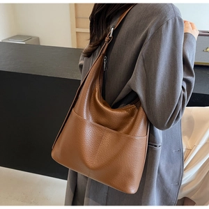 Braune Hobo-Tasche aus Leder mit Lychee-Muster, getragen mit grau-violettem Blazer