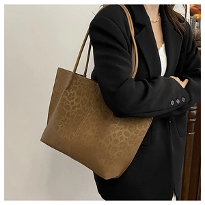 Detailed view of large leopard print tote bag styled with a black blazer on model