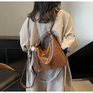 Detail of vintage brown leather tote bag with dual straps and sporty pendant accessory