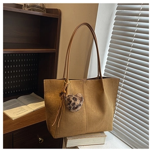 Detail view of brown suede tote bag with leopard print heart charm and leather tassel