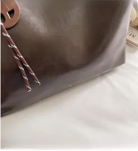 Detail der dunkelbraunen Leder-Tote-Bag mit feiner Textur und Marken-Schriftzug