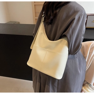 Detail der cremeweißen Leder-Tote-Bag mit Litschi-Textur zu einem grauen Blazer-Outfit