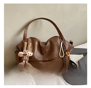 Detail of brown tote bag with textured faux leather, bunny charm and adjustable strap