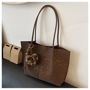 Close-up of leopard print tote bag with plush heart charm and tassel detail