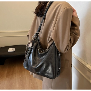 Detail of soft matte black tote bag with white fashion text and baseball charm
