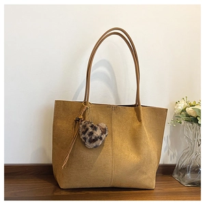 Detail of camel suede tote bag featuring a stylish leopard print heart plush keychain