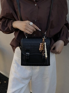 Women black woven crossbody bag with metallic buckles and colorful beaded pendant