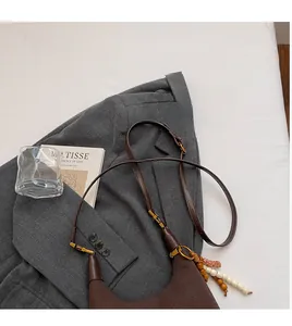 Détail du sac à main en daim marron avec bandoulière réglable et pendentif en perles