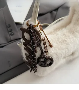 Detailansicht der beigen Plüschtasche mit braunem P-Anhänger und geflochtener Kordel