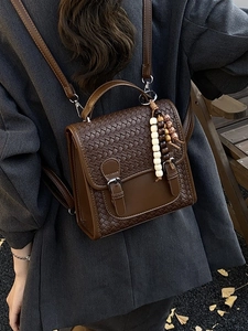 Brown woven PU leather backpack with buckle flap and beaded charm on model