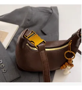 Détail du sac croissant en cuir marron foncé avec boucle dorée et perle en bois