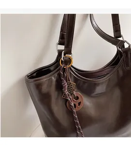 Detail der dunkelbraunen Leder-Shopper-Tasche mit Silberbeschlägen und Anhängern