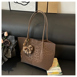 Close-up of leopard print leather tote bag on leather sofa with heart-shaped charm