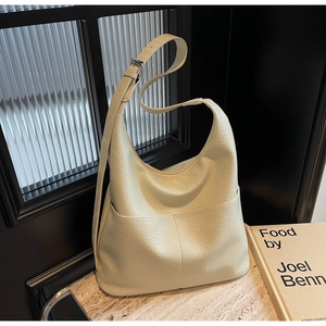 Detailansicht der beigen Lederhandtasche mit Lychee-Narbung und verstellbarem Riemen