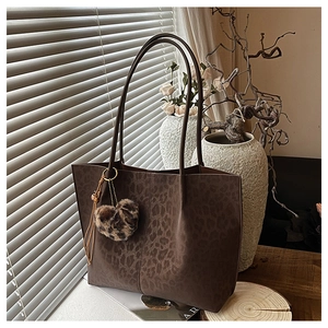 Detail of leopard print tote bag with heart charm and plush texture in warm sunlight
