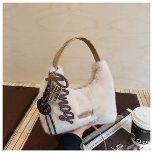 Detailansicht der flauschigen Handtasche mit Ledergriffen und Vintage-Anhängern