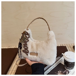 Detailansicht der flauschigen beigen Plüschhandtasche mit braunem Lederriemen und Label