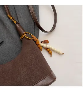 Gros plan du sac en daim marron foncé avec perles en bois et anneau métallique doré