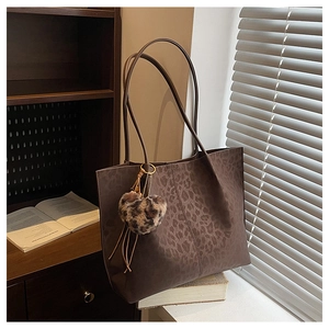 Detail of leopard print tote bag with plush heart charm and long shoulder straps