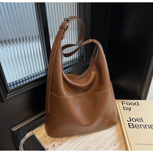 Detail der braunen Lychee-Ledertextur und des verstellbaren Riemens der Hobo-Tasche