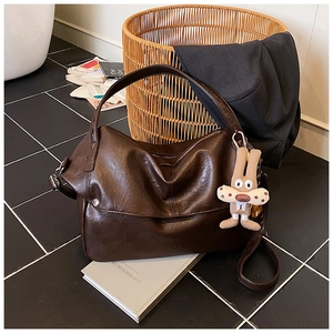 Detail of deep brown retro hobo bag with soft leather texture and plush rabbit charm