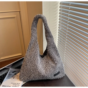 Detail of grey fuzzy knit tote bag with plush texture on dark tabletop surface