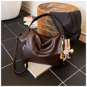 Detail of dark brown leather tote bag with rabbit charm on retro tile floor