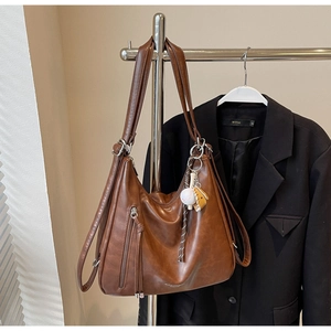 Close-up of vintage brown tote bag with zipper tassel and baseball themed pendant