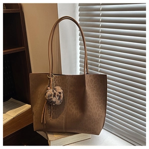 Detail of leopard print tote bag with soft texture and stylish fuzzy ball charm accessory