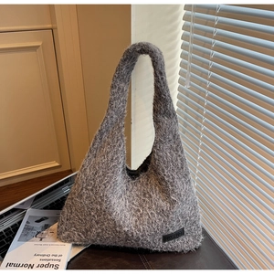 Close-up of grey plush hobo bag with JIASHUO leather logo on a modern office desk