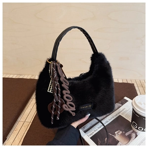 Detailansicht der schwarzen Kunstpelz-Handtasche mit Ledergriffen und Taschenanhänger