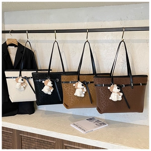 Macro shot of stylish tote bags in four colors with cute plush dog charms and metal buckles