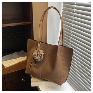 Detail of suede leopard print tote bag with plush heart charm and slim shoulder straps